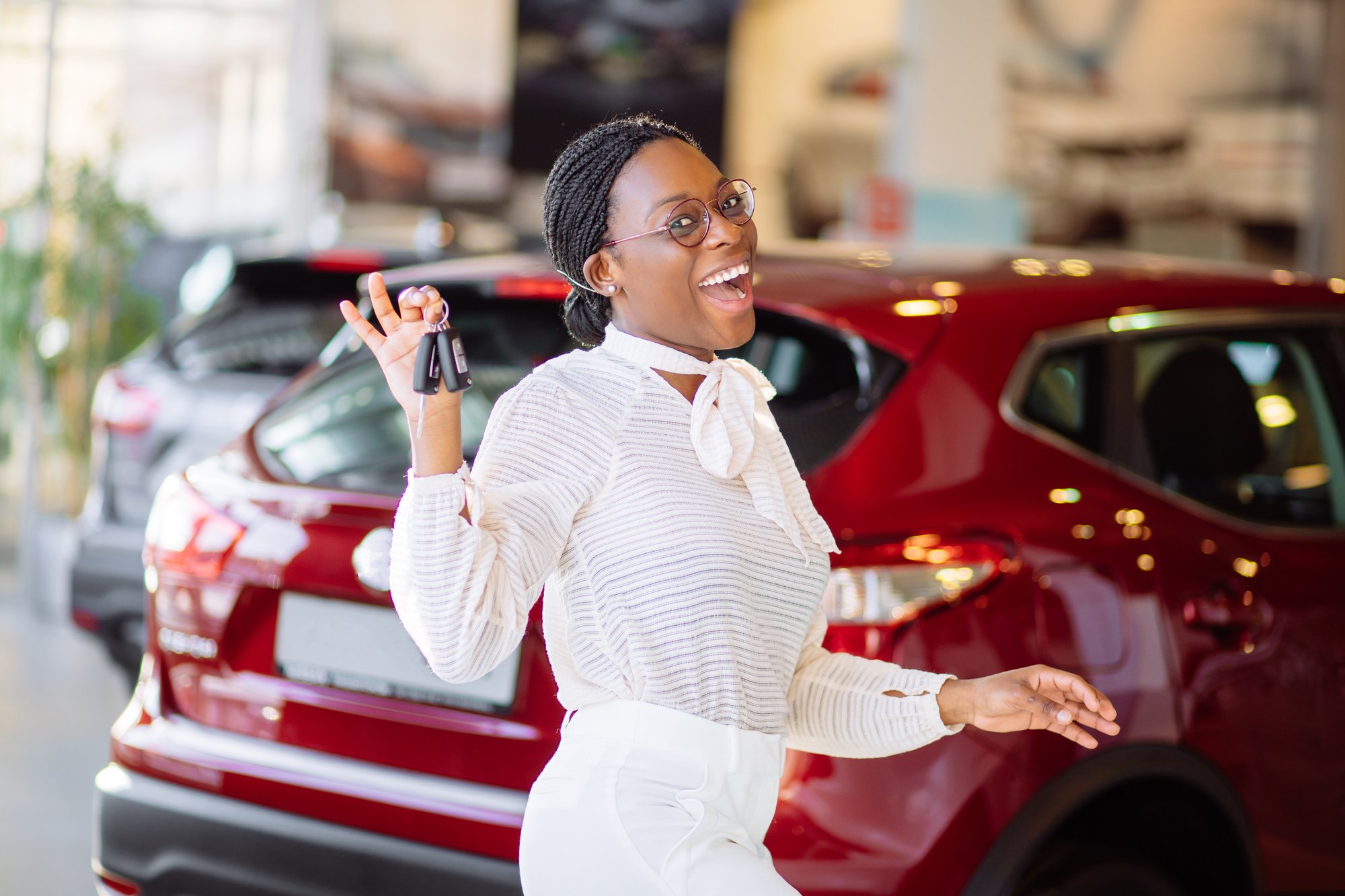 African woman with her new car showing key